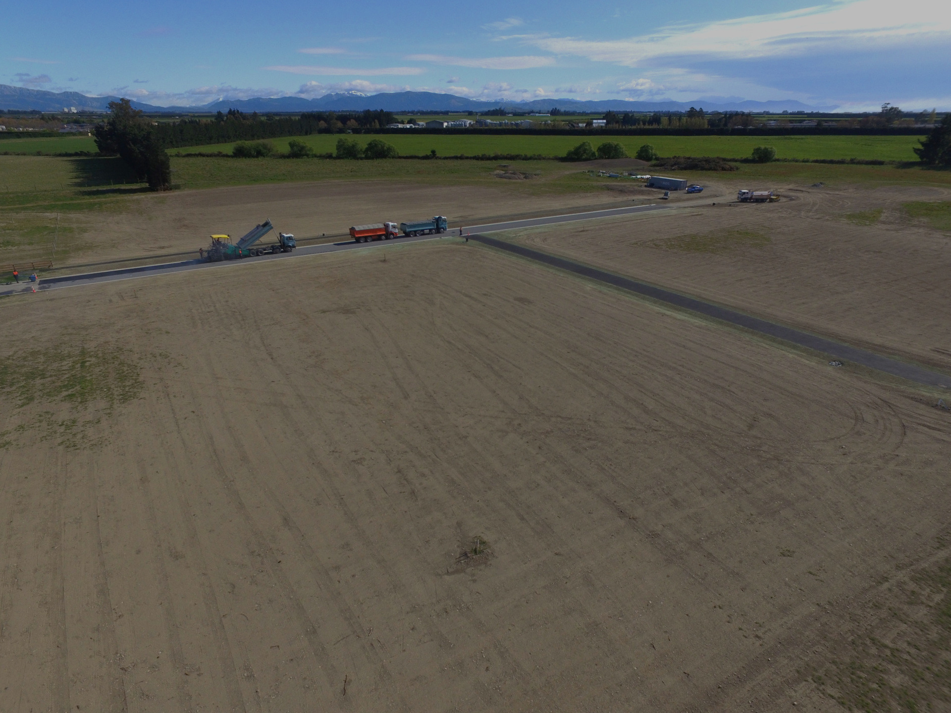 Aerial image of the Selwyn subdivision development by EDR Contracting showing a newly leveled stage with utilities and drainage installed, as crews spread final aggregate before paving.