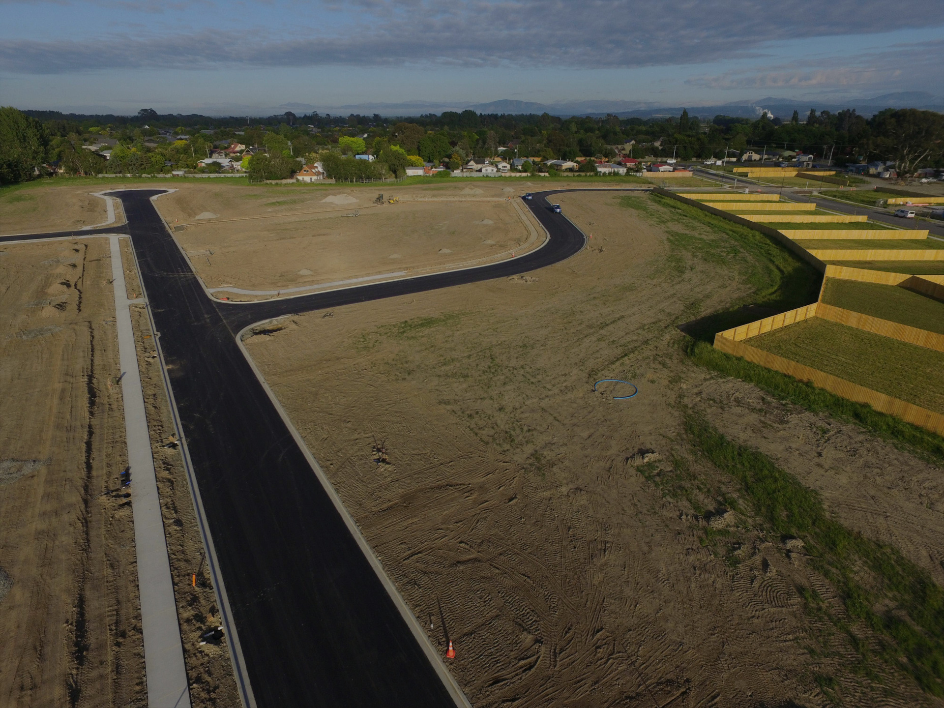 High aerial image of a Christchurch subdivision developed by EDR Contracting, showing finished roading, infrastructure, and footpaths on one side and fenced residential lots being built on the next stage awaiting grass seeding.